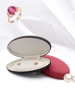 Macro view of oval matte jewelry box with pearl necklace and ruby gemstone ring