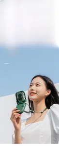 Detail showing the portable green mini fan used as a neck fan with a dedicated lanyard