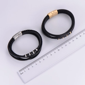Detail of multi-layer black braided leather bracelets with gold and silver magnetic clasps