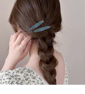 Gros plan de barrettes en acétate effet marbre sur une coiffure tressée brune