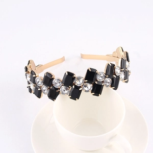 Detailed macro view of a gold-finish headband with black stones and clear rhinestones