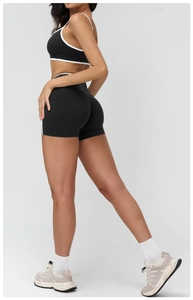 Detail of high-waist black yoga shorts with white piping for contouring and lifting