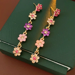 Detail of pink and purple floral tassel earrings with sparkling crystals on green box