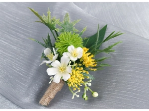 Close-up of white silk flowers and greenery boutonniere wrapped in rustic jute rope