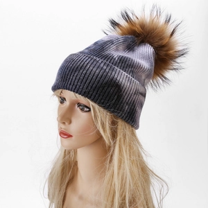 Close-up of tie-dye knit beanie with large faux fur pompom and ribbed texture detail