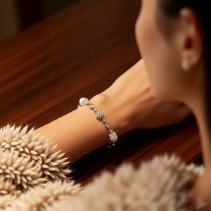 Detailed macro of a pearl bracelet with snowflake charm and purple stone on a model wrist