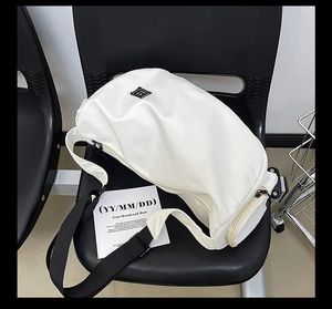 Detail of waterproof white crossbody bag with adjustable strap on a black chair