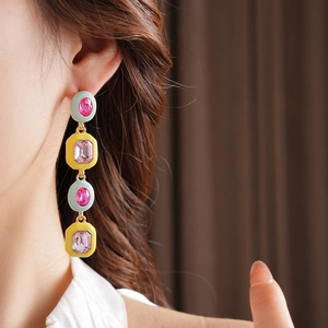 Detailed view of vintage gold-tone earrings with colorful gems and tassels on a model