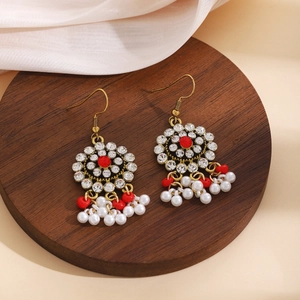 Detailed shot of ethnic long tassel earrings with red stones and white pearls on wood