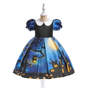 Detail of Halloween girl's dress featuring spooky castle and pumpkin prints on satin fabric