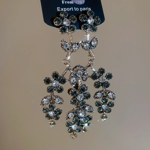 Macro view of vintage floral tassel earrings with green and white rhinestones