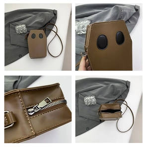 Detail view of coffin-shaped crossbody bag featuring ghost eye patches and metal zipper