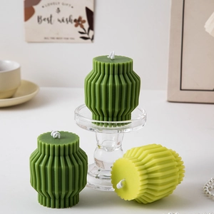 Close-up of green geometric pillar candles with ribbed texture and decorative accessories