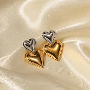 Elegant 18k gold and silver two-tone stainless steel heart earrings on silk background