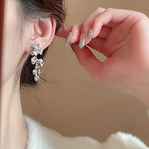 Close-up of silver irregular flower tassel earrings with layered metallic floral details