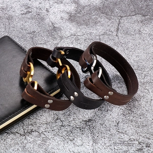 Close-up of leather anchor bracelets in black and brown with metal buckles on stone background