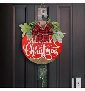 Detail of a Merry Christmas wooden door wreath with red plaid bow and green foliage