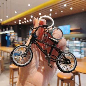 Close-up of a mini mountain bike keychain held in hand, featuring realistic black frame