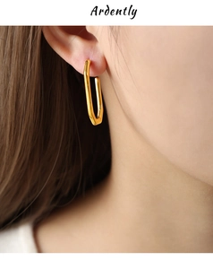 Close-up of minimalist gold U-shaped drop earring with a polished mirror finish on model