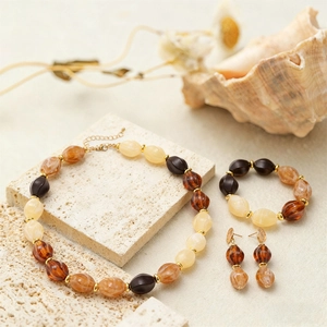 Retro bohemian acrylic oval bead jewelry set with amber tones on a travertine stone surface
