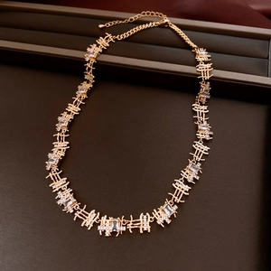 Close-up of golden geometric link necklace with zircons on a dark velvet display tray