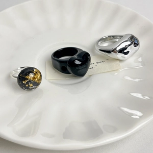Minimalist resin heart and silver irregular rings set in a white ceramic dish
