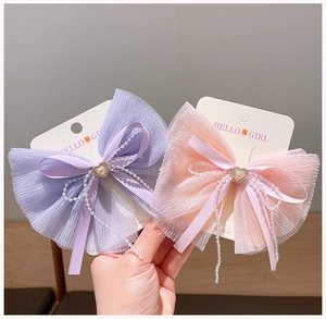 Detailed view of chiffon bow hair clips with pearl chains and heart-shaped buckles