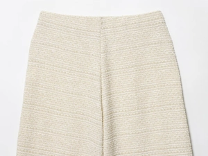 Détail du tissu en tweed texturé crème et de la couture à la taille de ce pantalon