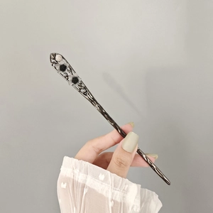Detailed view of an antique silver hair pin with delicate floral and pearl embellishments