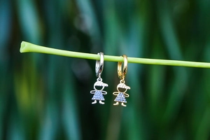Dettaglio macro di orecchini a cerchio con ciondolo ragazzo e ragazza in oro e argento