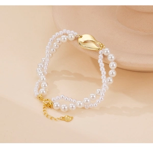 Dettaglio del bracciale di perle a doppio strato con ciondolo a cuore dorato e chiusura