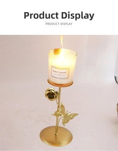 Golden iron candlestick holder with butterfly and rose details and burning candle