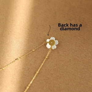 Macro shot of gold-plated white shell flower pendant back with a tiny inset crystal