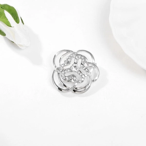 Elegant silver camellia brooch with rhinestones on a white background, top view