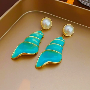 Detail of vintage gold sea shell earring with light blue enamel and faux pearl inlay