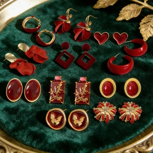 Collection of red petal earrings with gold tassels and stones on dark green velvet base
