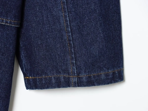 Gros plan sur les coutures jaunes contrastées du tissu en denim bleu foncé d'une jupe longue