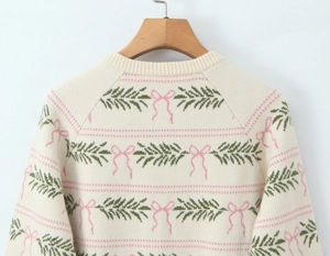 Close-up of cream knit sweater with pink bow patterns and green leaf jacquard details