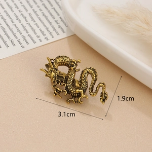 Detailed view of a 3.1cm gold dragon brooch on a ceramic tray with vintage dried flowers