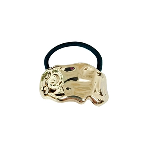 Detail of minimalist golden organic irregular metal charm on high-elastic black hair tie