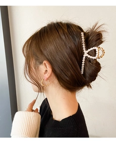 Close-up of a hair claw clip featuring large pearls and gold metal finish for elegant buns