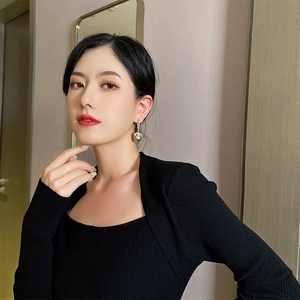Elegant gold drop earrings with large deep purple pearls on a model in a black sweater