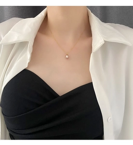 Detail shot of a natural pearl pendant on a thin gold titanium necklace worn by a model