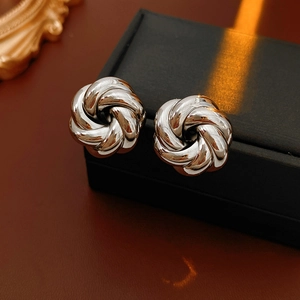 Detailed close-up of silver metal vortex flower earrings on a black display box