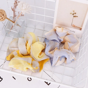 Detail view of checkered scrunchies in yellow and blue colors placed in a white basket
