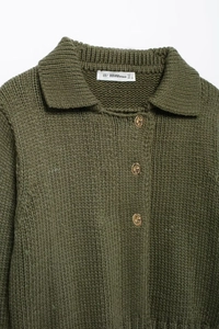 Dettaglio del colletto del cardigan verde in maglia con bottoni dorati e trama fine