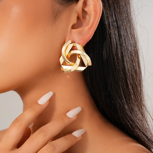 Close-up of geometric gold-toned hoop earrings worn by a model for a chic metallic look