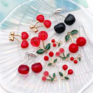 Detail of red cherry pendants with metal hooks and glossy resin finish for jewelry DIY