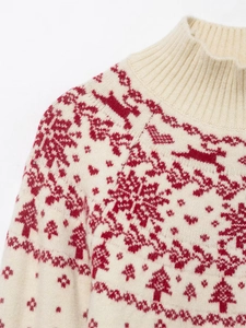 Detail of a beige Christmas sweater with red reindeer and tree jacquard knit patterns