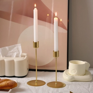 Modern gold metal candle holder set with round base and white candles for dining decor